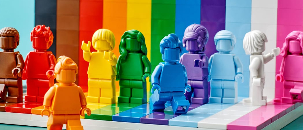 Colourful rainbow Lego figurines representing diverse workplace characters gathered in a circle, symbolising a supportive and inclusive work culture.