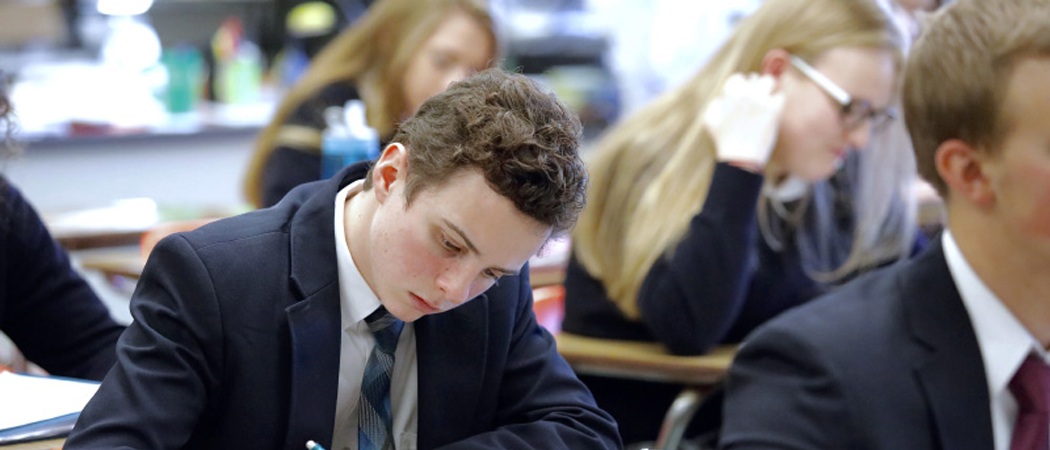 Co-educational high school students focused and sitting an important exam, symbolising resilience and mental toughness in academic success.