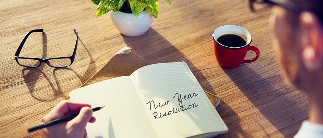 Open diary on a wooden table with “New Year Resolution” written on the page in cursive.