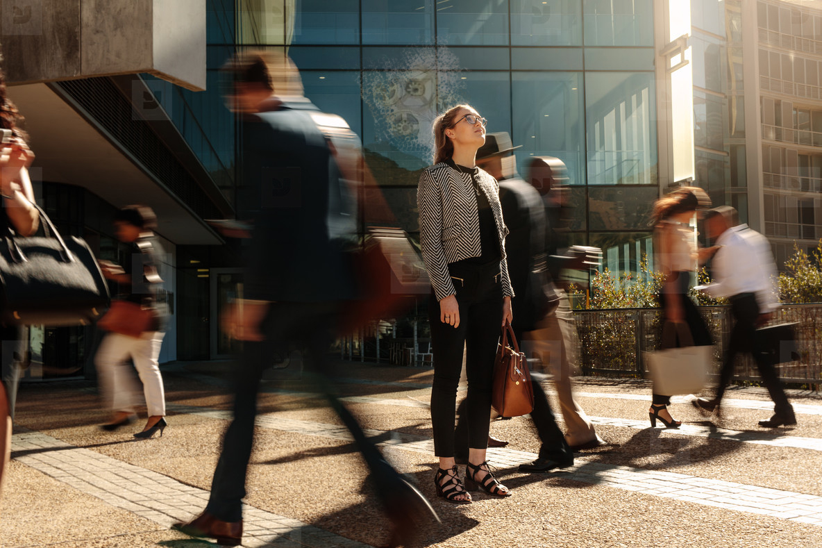 Professional woman gazing upward in a vibrant cityscape, symbolising clarity, ambition, and mental strength.