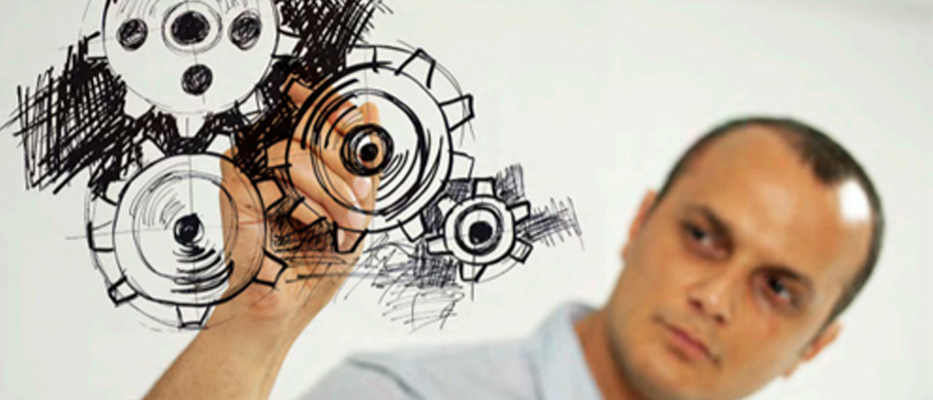 Professional man drawing interlinked cogs on glass panel to represent workplace systems and pressure points.