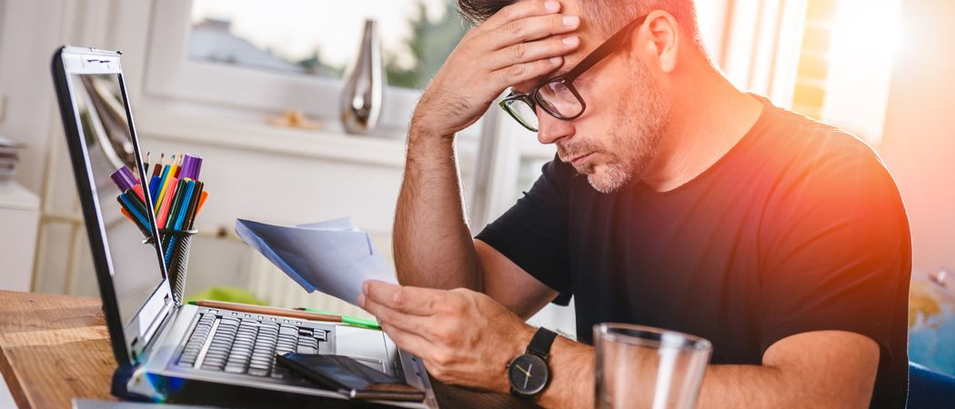 Stressed professional man sitting at home office desk, showing signs of burnout.