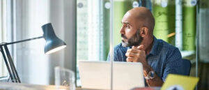 Professional male leader in office reflecting thoughtfully, illustrating self-awareness and leadership growth.