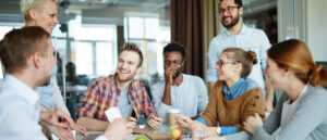 A team of office workers collaborating at a desk in a psychologically safe and supportive workplace environment.