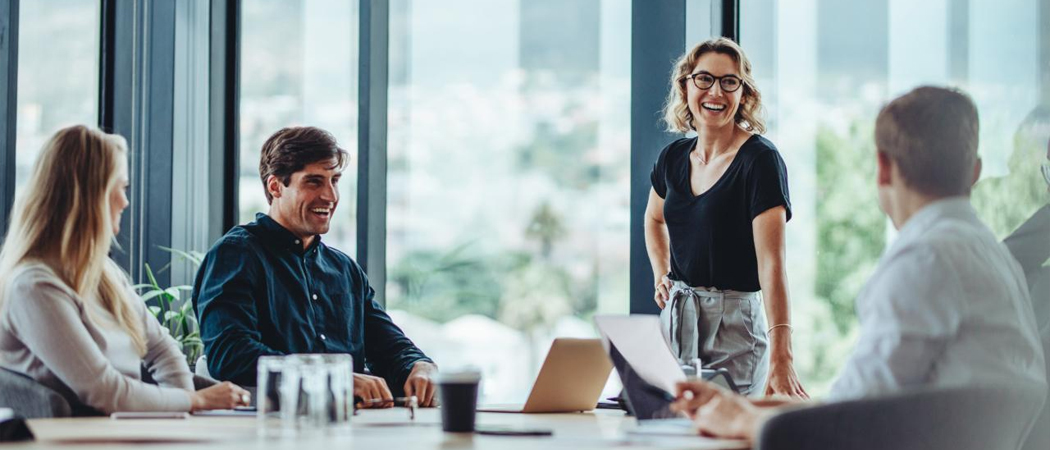 Four diverse professionals discussing workplace psychosocial hazards around a table.