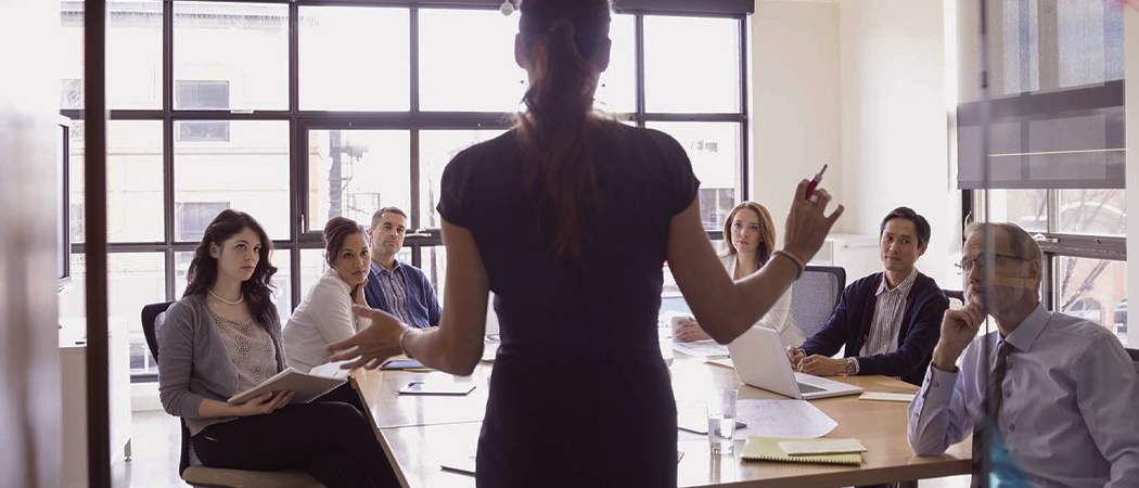 Female executive leader addressing her executive team on controlling psychosocial hazards and enhancing leadership capability in the workplace.