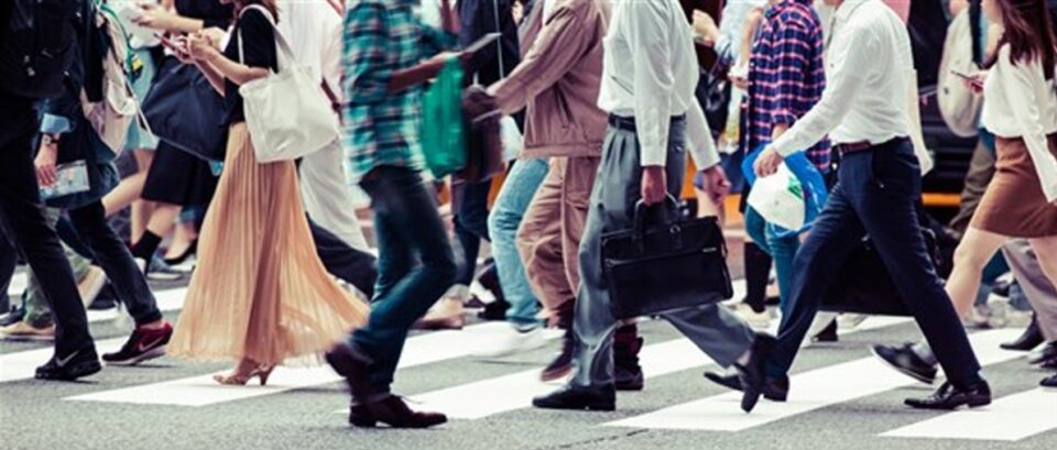 “Professional walking along a busy city pavement, representing the everyday application of character strengths and personal virtues.”