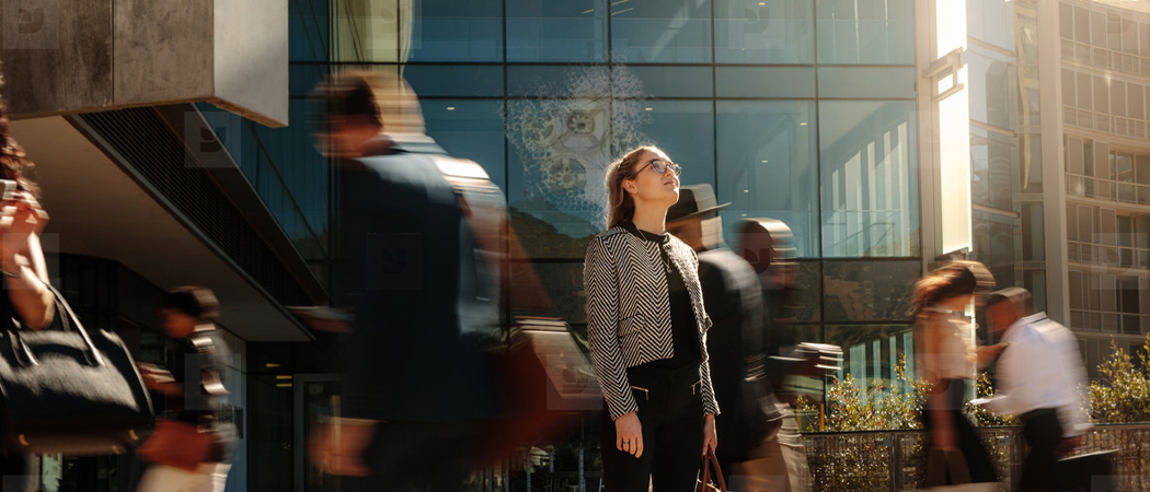 Professional woman gazing upward in a vibrant cityscape, symbolising clarity, ambition, and mental strength.