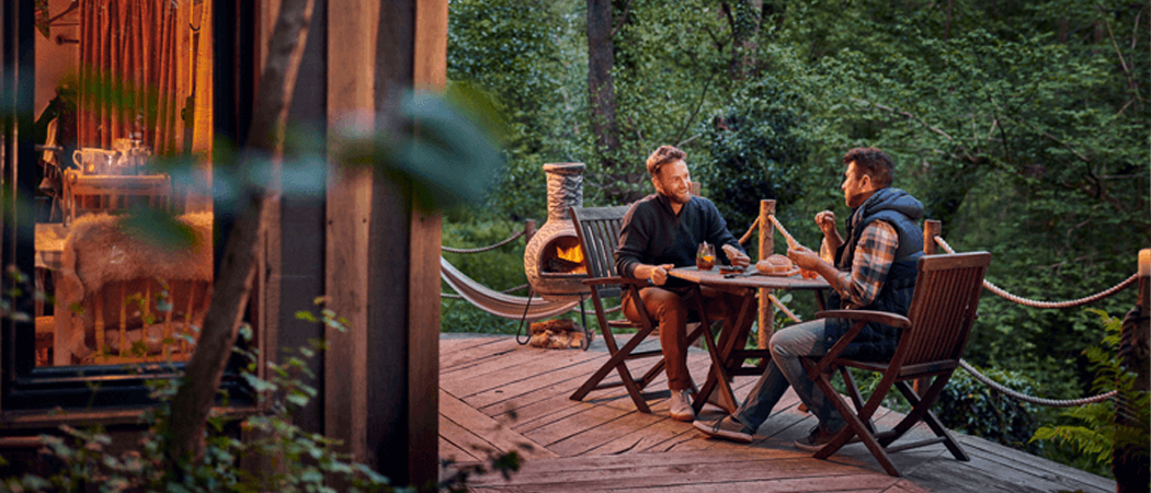 Two men enjoying a forest retreat, unplugged from devices, immersed in nature and conversation during a digital detox.