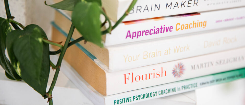A stack of professional development books on a desk, symbolising the pursuit of personal growth and lifelong learning.