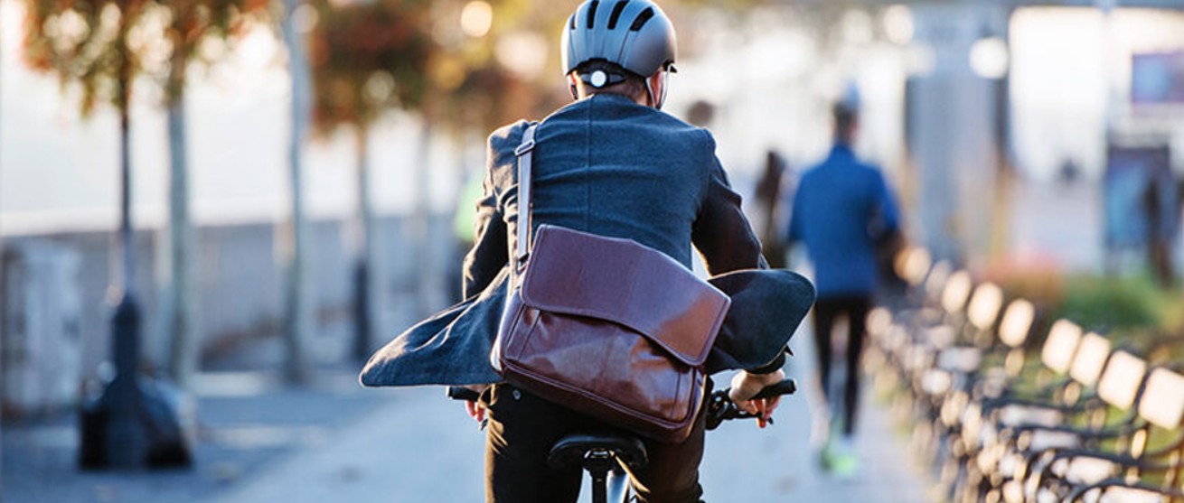 Professional man riding bike to work through a city park in a suit, embracing holiday energy at work.
