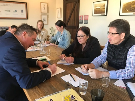 Paradise Resort leaders engaged in a collaborative group exercise during a Get Mentally Fit leadership training session around a long wooden table.