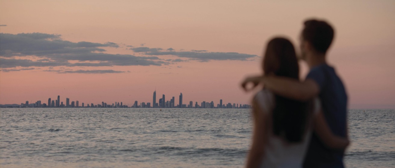 Couple standing together on the beach at sunset, reflecting and talking calmly.