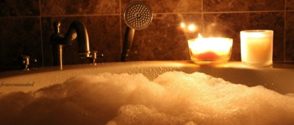 A serene bath surrounded by glowing candles, creating a calming atmosphere for rest and quiet reflection.