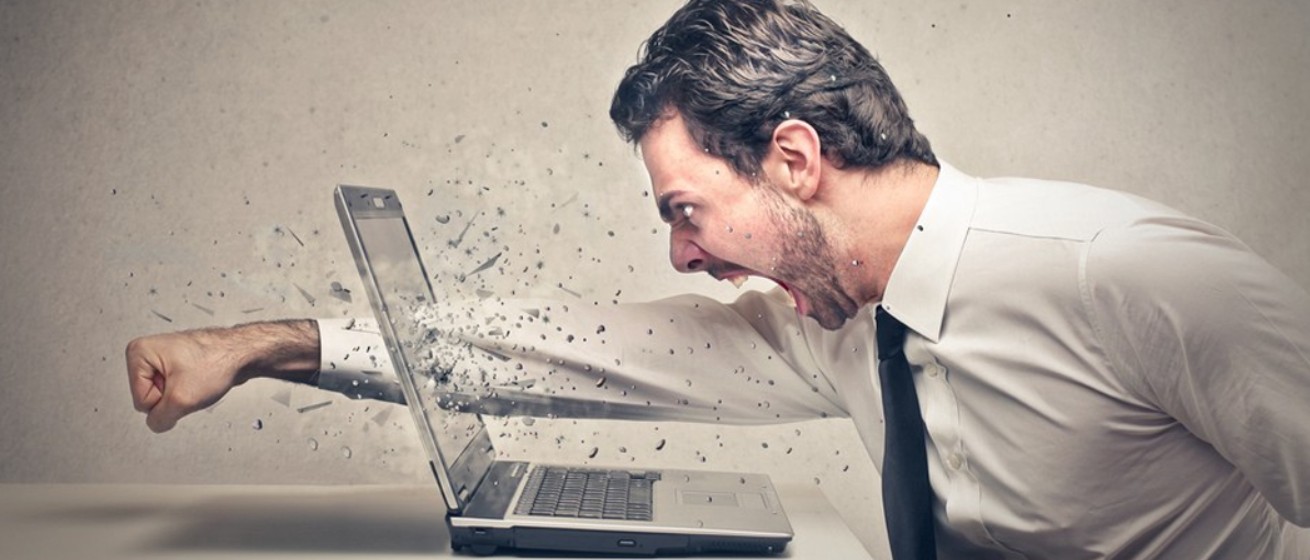 Stressed businessman breaking through laptop with determination, symbolising you can Change Your Brain with Mental Imagery.
