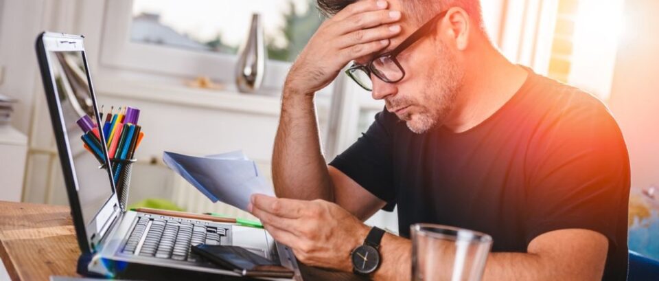A professional man sitting at a desk with a laptop, looking focused and slightly overwhelmed as he tries to finish work before the holiday break.