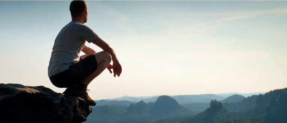 A hiker standing at the summit of a mountain, peacefully taking in the expansive view after a long climb. Mental wellbeing tools for the festive season.